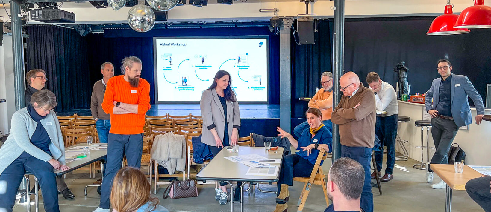 Dieses Bild zeigt ca. 15 Personen, die an einem Workshop miteinander diskutieren.